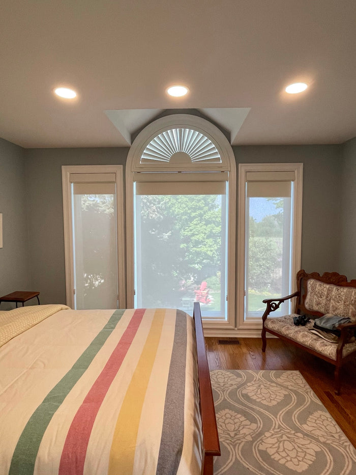 This client opted to combine a few styles of window dressing to suit their needs. A custom stationary cellular shade for the specialty arch and double roller shades - one set of sheer shades for privacy and light filtering with another set of blackout roller shades to block the light ~ allowing a few extra hours of sleep